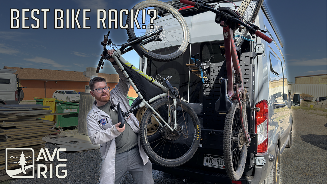 Black metal Tokul Racks bike rack system mounted to the rear of a silver camper van.