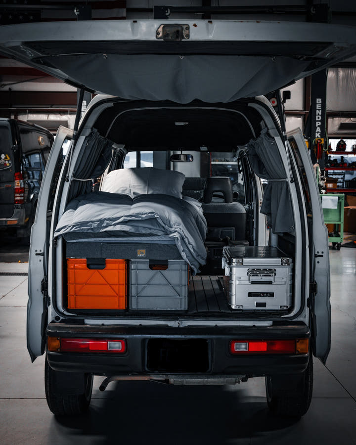 SidioCrate grey and orange storage bins in the back of a camper van under a bed.