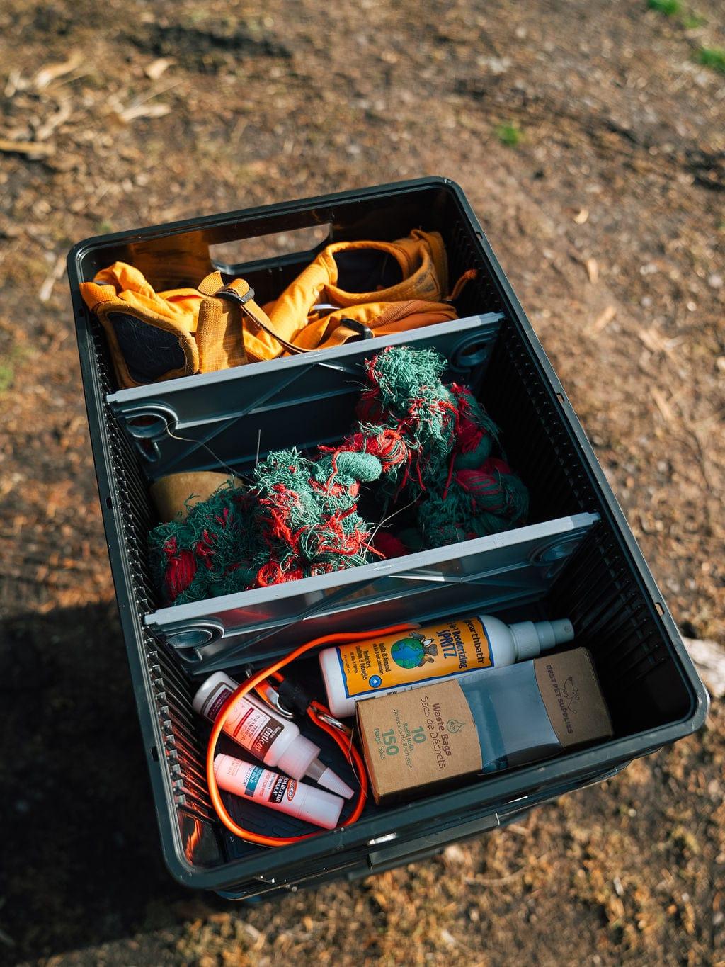 Black SidioCrate storage organizer with dividers containing gear like ropes and camping supplies.